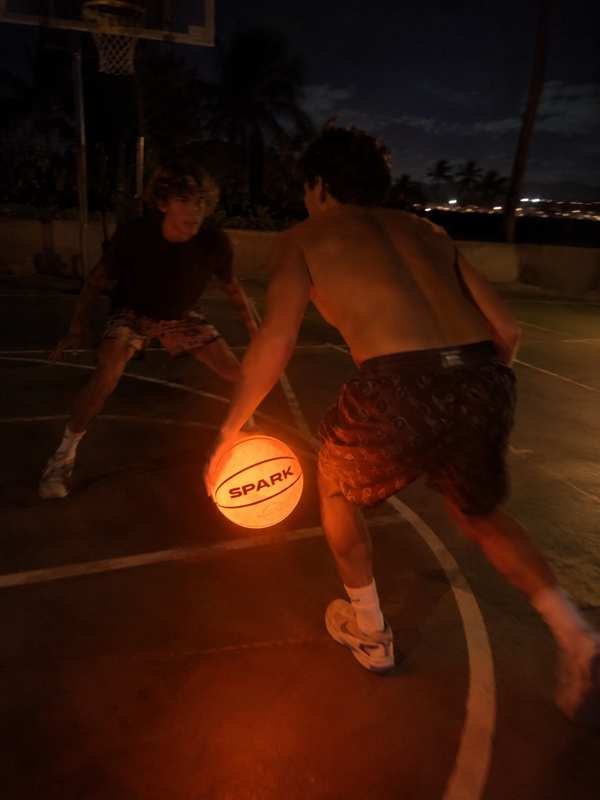 Players on a court at night with a glowing SPARK LED basketball
